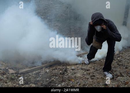 Kendari, Sulawesi du Sud-est, Indonésie. 11th avril 2022. Un démonstrateur a tenté de couper le gaz lacrymogène en le faisant marcher. La manifestation du 11 avril, qui a été menée simultanément par des étudiants dans différentes provinces d'Indonésie, s'est d'abord bien déroulée, mais après quelques heures, la foule a commencé à se révolter et a jeté des pierres sur les officiers, qui ont répondu par des gaz lacrymogènes. (Credit image: © Andry Denisah/ZUMA Press Wire) Banque D'Images