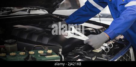 Un mécanicien de voiture effectue une réparation de voiture dans un atelier de réparation. Banque D'Images