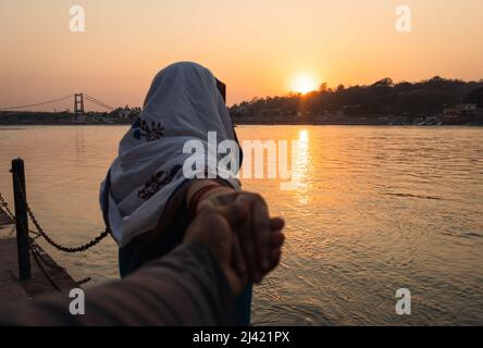 un jeune couple tenant des mains au coucher du soleil sur la rive du gange à partir de différentes images d'angle est pris à la rive du ganga rishikesh uttrakhhand inde. Banque D'Images