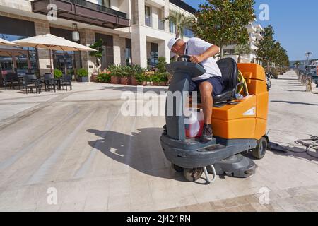 TIVAT, MONTÉNÉGRO - 15 JUILLET 2021 : un ouvrier lave les trottoirs sur une machine de nettoyage spéciale Taski Banque D'Images