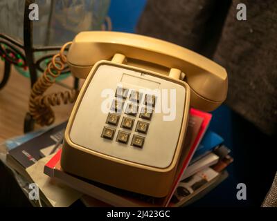 Vieux téléphone avec un clavier crème sur une table au-dessus de quelques livres Banque D'Images