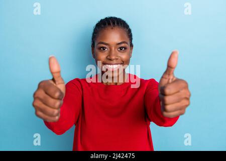 Photo de doux jeunes traids ladesdo dame pouce vers le haut de l'appareil photo porter rouge pull-over isolé sur fond bleu de couleur Banque D'Images