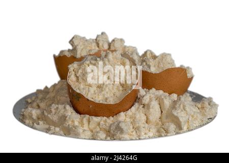 Poudre de protéine d'œuf sur une plaque et coquilles d'œuf isolées sur fond blanc. Nutrition sportive. Banque D'Images