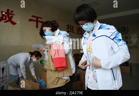 (220411) -- TIANJIN, le 11 avril 2022 (Xinhua) -- Xu Ning (1st R) met sur l'uniforme d'équipe avant de partir pour Shanghai, dans le nord de la Chine Tianjin, le 11 avril 2022. Tianjin a envoyé lundi une équipe de 78 travailleurs médicaux de médecine traditionnelle chinoise (TCM) pour aider Shanghai à lutter contre la pandémie COVID-19. Xu Ning, médecin en chef adjoint du premier hôpital d'enseignement de l'Université de médecine traditionnelle chinoise de Tianjin, en est l'un d'entre eux. Au cours des deux dernières années, elle a travaillé dans les quartiers de l'hôpital Tianjin Haihe à plusieurs reprises pour lutter contre la pandémie et a acquis beaucoup d'expérience dans le traitement de la MCT. ( Banque D'Images