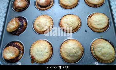 HAYDOCK. MERSEYSIDE. ANGLETERRE. 12-07-21. Une plaque de tartes maison fraîchement confecES au four avec la garniture débordant de certains d'entre eux. Banque D'Images