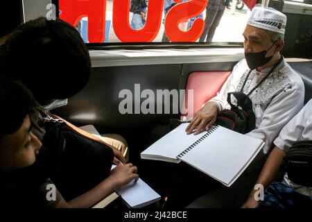 Surabaya, Indonésie. 11th avril 2022. Les personnes malvoyantes lisent le Coran écrit en braille lorsqu'elles participent à une visite en bus du Ramadan pendant le mois Saint du Ramadan à Surabaya, Java-est, Indonésie, le 11 avril 2022. La lecture de Coran écrit en braille dans les transports publics fait partie d'une campagne visant à appeler à un accès amical pour les personnes handicapées. Credit: Kurniawan/Xinhua/Alay Live News Banque D'Images