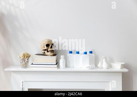 Les bouteilles blanches avec un distributeur bleu avec shampooing, après-shampooing, crème et savon liquide sont sur une étagère dans la salle de bains. Crâne sur le mou des livres Banque D'Images