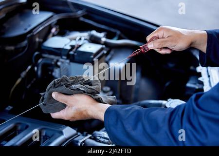 Vérification de l'huile. Vue en grand angle d'un mécanicien mâle méconnaissable travaillant sur le moteur d'une voiture pendant un entretien. Banque D'Images