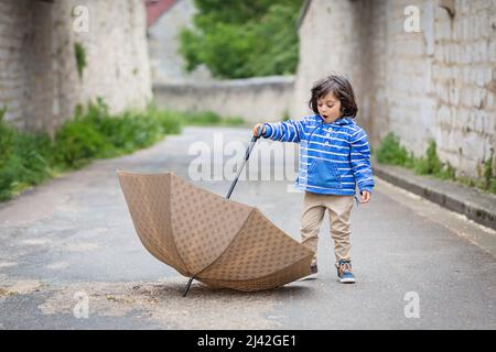 Petit garçon de l'est beau jouer avec un parapluie extérieur Banque D'Images