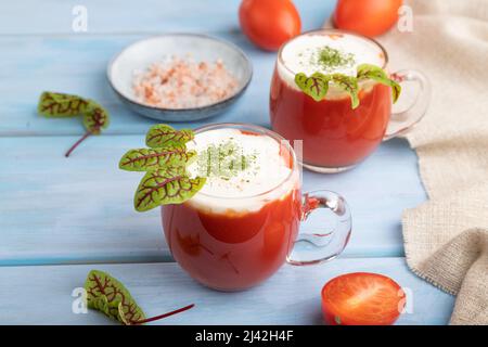 Jus de tomate avec sorrel, sel himalayan et crème aigre en verre sur fond de bois bleu avec textile lin. Concept de boisson saine. Vue latérale, fermer Banque D'Images