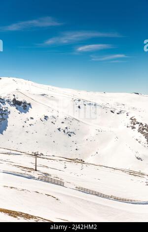 Vue sur la Sierra Nevada, Grenade, Andalousie, Espagne. Montagnes enneigées, jour ensoleillé. Pistes de ski et télésiège. Paysage d'hiver avec neige. Banque D'Images