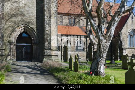 Église Saint-Nicolas avec vue sur les pierres tombales et flanquée de pelouses et d'arbres sous le ciel bleu sur une belle source ensoleillée morninbg à Beverley, Yorkshire, Royaume-Uni. Banque D'Images