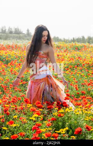 Jeune fille, cheveux longs heureux dans le champ de pavot de printemps Banque D'Images