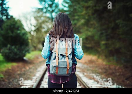 La nature est là où elle aime se demander. Vue arrière d'une femme méconnue qui marche sur les voies de train à l'extérieur. Banque D'Images