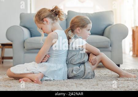 Je vais dire à maman. Photo de deux petites filles assises dos à dos et regardant en colère à la maison. Banque D'Images