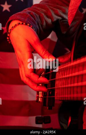 mains jouant une guitare électrique avec une lumière rouge Banque D'Images