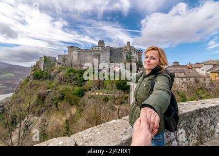 Une femme blonde tient une main masculine, avec le château de Bardi en arrière-plan, Parme, Italie Banque D'Images