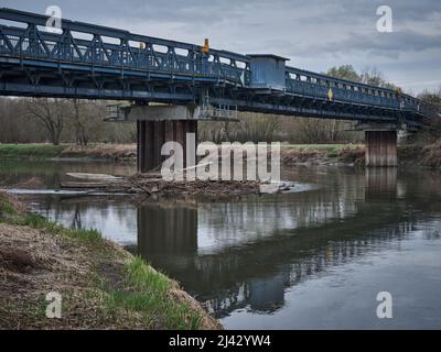 Pont en métal bleu sur la rivière Morava avec du bois flotté capturé sur un pilier en Slovaquie. Banque D'Images