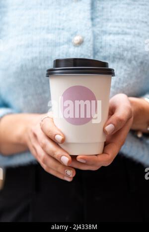 La main jeune femelle tient une tasse de papier de café, à emporter. Banque D'Images