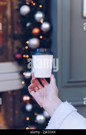 La main jeune femelle tient une tasse de papier de café, à emporter. Banque D'Images