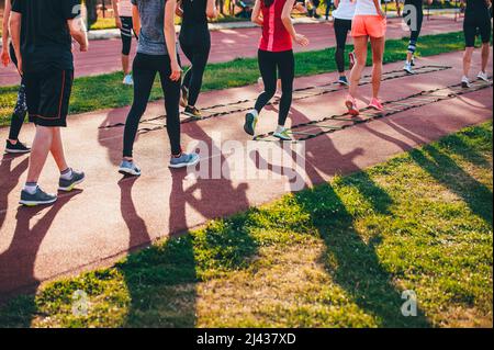 Perceuses à échelle. Entraînement d'équipe en plein air sur une piste sportive. Entraînement féminin dans la nature, lumière chaude du coucher du soleil Banque D'Images