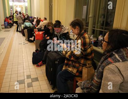Przemysl, Pologne. 12th avril 2022. La gare de Przsemysl (Przemysl Glowny en polonais) a été emballée à nouveau ce soir, 04/11/2022, avec un train complet de réfugiés ukrainiens de Kiev entrant, et beaucoup ont été victimes de l'attentat à la gare de Kramatorsk ce week-end; d'autres de Bucha, une ville de l'armée de Poutine s'est transformée en un site de masse. Ici, les gens communiquent avec leurs proches sur leur téléphone « » ils peuvent tous obtenir des cartes SIM polonaises gratuites ici » » » ou ils parlent les uns avec les autres, ou se reposer en attendant de monter à bord des trains vers les villes de leur choix. Certains ont plus dans le traitement à faire et finissent vers l'abri Banque D'Images