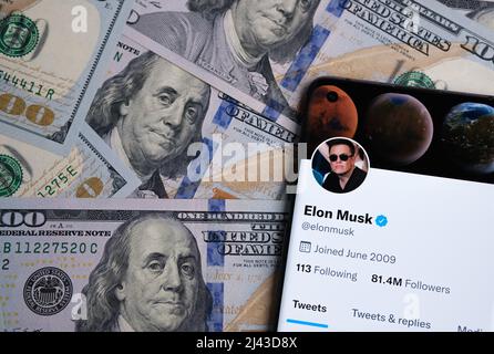 La page officielle du compte twitter d'Elon Musk est affichée sur le smartphone qui est placé sur la pile de billets en dollars. Concept. Stafford, Royaume-Uni, A Banque D'Images