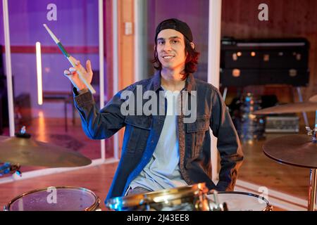 Portrait d'un jeune musicien talentueux jouant de la batterie dans un studio d'enregistrement et souriant Banque D'Images