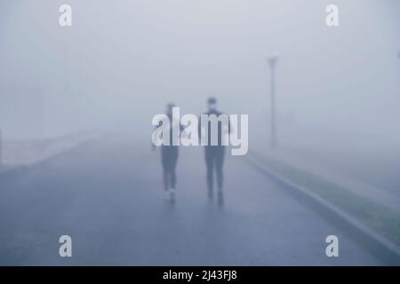 Deux athlètes coureurs qui s'entraînent le long de la route pour s'entraîner par temps brumeux. Photo de haute qualité Banque D'Images
