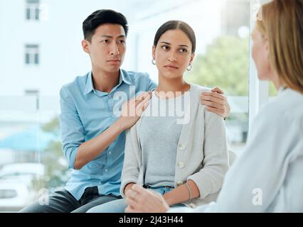 Il doit y avoir quelque chose que vous pouvez faire. Prise de vue d'un médecin mature réconfortant un jeune couple tout en délivrant de mauvaises nouvelles au travail. Banque D'Images