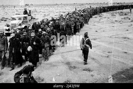 La bataille de Libye Une longue ligne de prisonniers (tous allemands dans les plafonds à pic) est passée des zones en avant à un point de concentration en route pour un campement de prisonnier de guerre. 14 décembre 1941. (Photo d'un responsable britannique). Banque D'Images