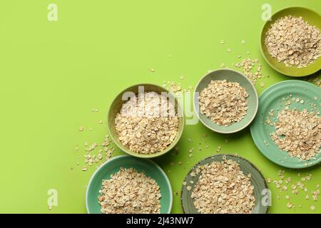 Assiettes et bols de flocons d'avoine crus sur fond vert Banque D'Images