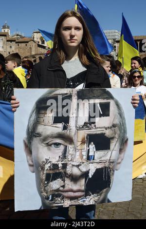 Rome, Italie. 10th avril 2022. Le fait de détenir une image d'un bâtiment endommagé par une bombe au-dessus de Putins fait face à un membre de la communauté romaine ukrainienne à Rome, qui proteste contre l'invasion russe de l'Ukraine. (Image de crédit : © Evandro Inetti/ZUMA Press Wire) Banque D'Images