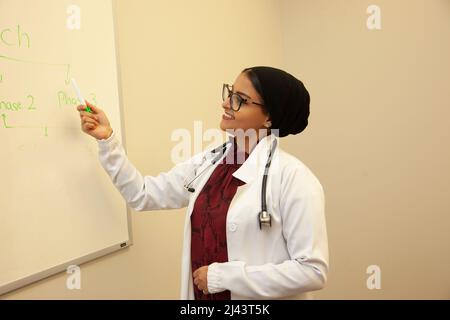 le médecin portant un hijab enseigne ou explantation quelque chose dans la classe Banque D'Images