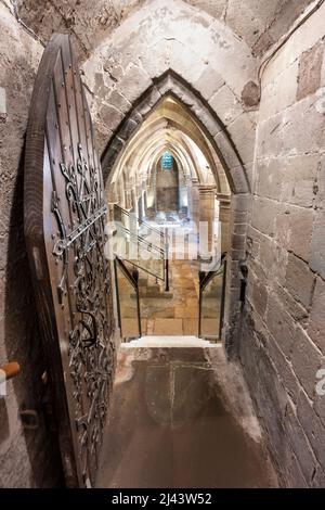 Porte en bois ouvrée, menant à une crypte ancienne élégamment éclairée, sous l'église de la cathédrale du diocèse anglican de Hereford Banque D'Images