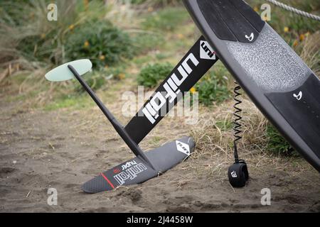 Une planche de surf hydrofoil en fibre de carbone avec hydrofoil en fibre de carbone et laisse se trouve sur le sable à Piha Beach, Auckland, Nouvelle-Zélande. Banque D'Images