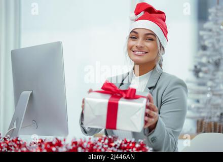 Noël soigneusement emballé. Portrait d'une jeune belle femme qui répande la joie de Noël avec des cadeaux au bureau. Banque D'Images