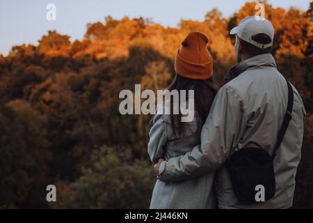 Jeune couple assis sur le banc et regardant loin en automne Banque D'Images