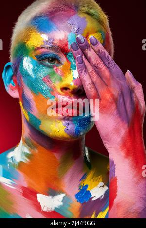 C'est une raison pour laquelle nous ne voyons pas le monde en noir et blanc. Photo studio d'une jeune femme posant avec de la peinture multicolore sur son visage. Banque D'Images