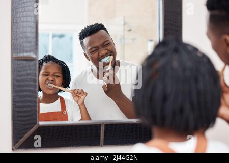 Assurez-vous d'avoir chaque dent. Photo d'un jeune père qui se joint à sa fille pendant qu'ils se brossent les dents dans la salle de bains à la maison. Banque D'Images