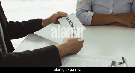 Une femme prend la poignée à l'enveloppe de démission tout en étant remise à la femme gestionnaire. Banque D'Images