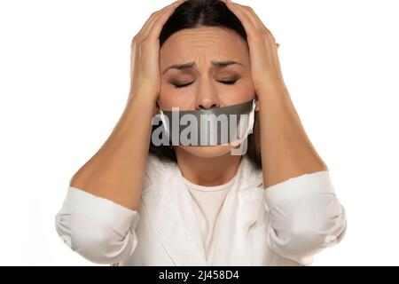 Jeune femme malheureuse avec du ruban adhésif sur sa bouche sur un fond blanc Banque D'Images