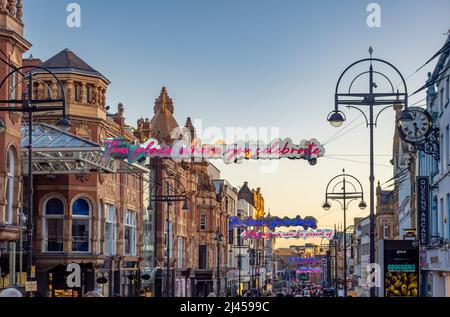 Des enseignes lumineuses au néon sont suspendues à Briggate, au crépuscule. Leeds, Royaume-Uni Banque D'Images