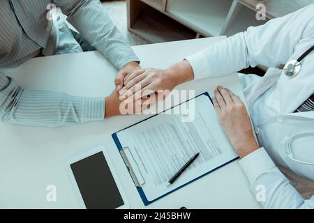 Le médecin a serré les mains et consolé les patients qui s'inquiétaient du traitement. Banque D'Images