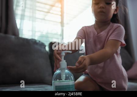 Enfant asiatique utilisant le désinfectant pour les mains, distributeur de gel à l'alcool à la maison pendant l'épidémie de coronavirus. Banque D'Images