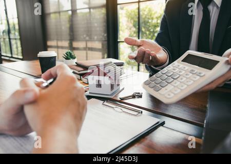 Les agents calculent le taux de paiement du prêt ou le montant des primes d'assurance pour les clients qui viennent contacter l'achat d'une nouvelle maison à l'extérieur Banque D'Images