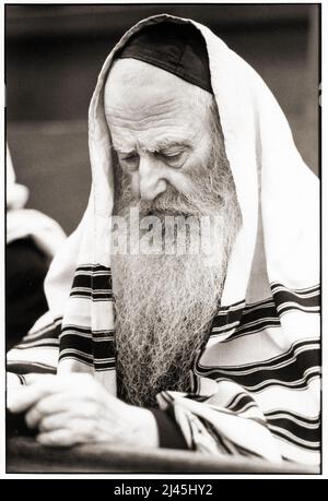 Un juif orthodoxe, probablement un rabbin, lit de son livre de prière pendant les services du matin de vacances de Sukkos au siège de Lubavitch à Brooklyn, 1983. Banque D'Images