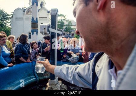 Les gens récoltent l'eau d'une source sainte dans les terres de la Trinité Lavra de Saint-Sergius, le plus important monastère russe de l'Église orthodoxe russe, à Sergiyev Posad, à 70 km de Moscou. Mai 1990 Banque D'Images