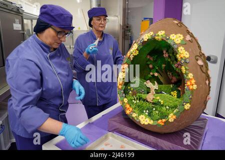 Dawn Jenks et Donna Oluban, chocolatiers du monde de Cadbury, ajoutent la touche finale à leur création de chocolat sur le thème de Pâques à Cadbury World à Birmingham. Date de la photo: Mardi 12 avril 2022. Banque D'Images