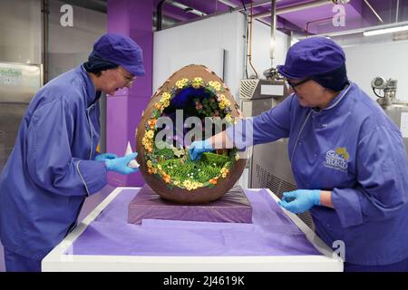 Dawn Jenks et Donna Oluban, chocolatiers du monde de Cadbury, ajoutent la touche finale à leur création de chocolat sur le thème de Pâques à Cadbury World à Birmingham. Date de la photo: Mardi 12 avril 2022. Banque D'Images